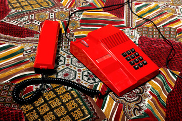 Vintage red telephone on a colorful patterned surface representing nostalgia and communication