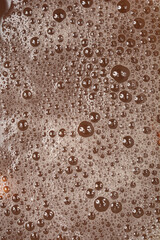 A close-up shot captures the frothy surface of dark liquid filled with numerous small and large bubbles