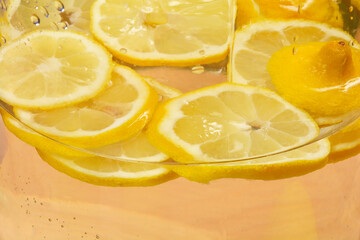 Several lemon slices are submerged in clear water within a glass container
