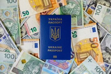 ukraine passport on a pile of euro, usd and polish zloty banknotes, global finance and travel concept