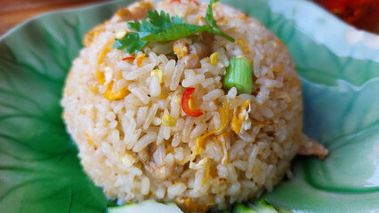 Close-up of a serving of thai fried rice garnished with coriander and spring onions, showcasing the vibrant colors and textures of the dish