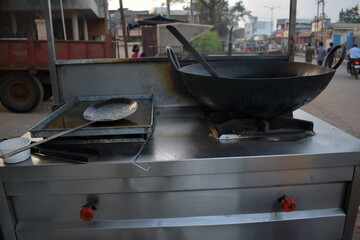 A street vendor's cooking station showcases a large frying pan with oil, ready for food preparation...
