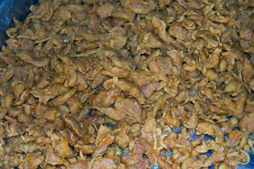 A large tray filled with golden-brown crispy fried snacks arranged for sale in a vibrant food market setting