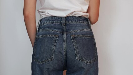 A young woman pulls out a smartphone from the back pocket of her jeans.