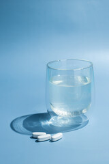 tablets with a glass of water on blue background