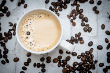 Top-down view of a delicious cup of coffee next to scattered coffee beans—perfect for café promotions, morning routines, and coffee lover content. Warm, inviting, and full of aroma.