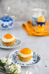 Lemon cupcakes with cream cheese, apricot and poppy seed. Cupcake in form of Fried Egg on a stone background. Easter eggs. Easter holiday and festive food.