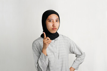 Southeast Asian Muslim woman in headscarf pointing with serious face like giving warning or advice....