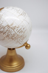 White decorative globe with golden elements on white background. Minimal travel and freelance concept symbolizing global connection and exploration.