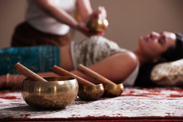 Woman undergoing singing bowl therapy indoors, selective focus