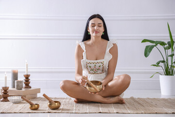 Woman with singing bowls on floor indoors