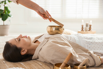 Woman undergoing singing bowl therapy lying on floor indoors
