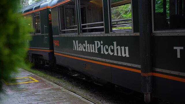 Passenger Train with Machu Picchu Sign on the Tracks in Aguas Calientes, Peru During Rain