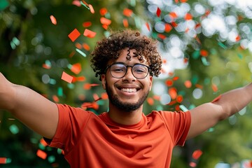 A man in an orange shirt is smiling and surrounded by confetti