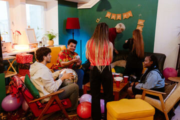 A multinational group of young people preparing for a lively birthday party in a cozy, colorful...