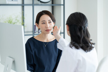 美容外科で診察を受けるミドルの女性