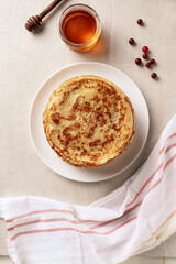 Crepes, thin pancakes with honey on a white plate. Marble background. Top view.