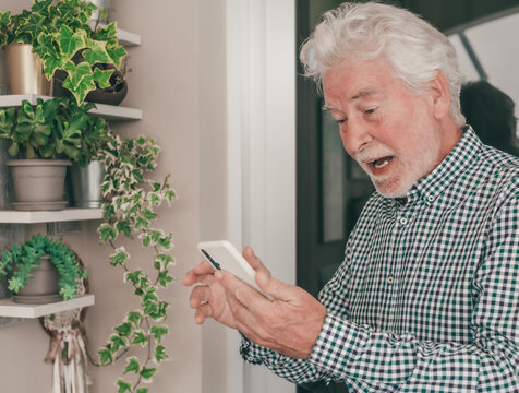 Happy Video Call. Heart-Warming Connections for a surprised senior bearded grandfather using smartphone to stay in touch with distant family or friend
