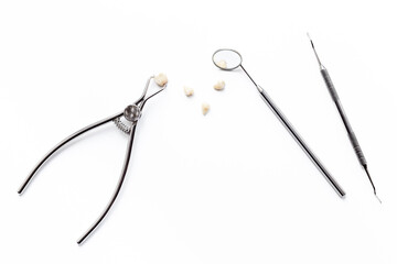 Dental teeth crowns and steel instruments for dental prosthetics, top view. Dentist desk, white background