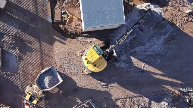 Aerial view of excavator loading dumper with crushed stone gravel