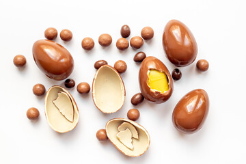 Broken and whole chocolate egg on white background, top view. Chocolate background