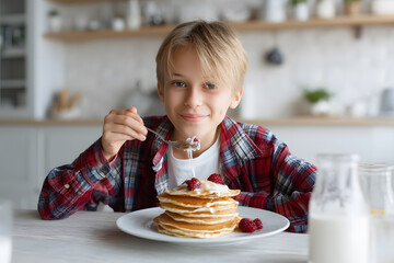 A young boy is eating pancakes with strawberries on top