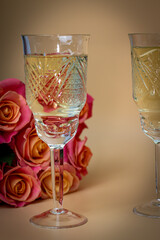 Vertical photo of two glasses and roses on a light background, romantic setting, side view
