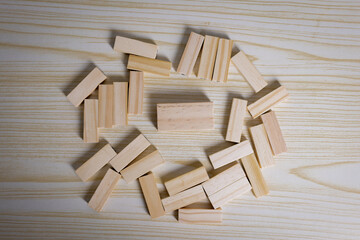 Scattered wooden blocks on a light wooden table, symbolizing creativity, brainstorming, construction, teamwork, or starting from scratch with endless possibilities.