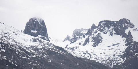 Snowy mountain landscape with rugged peaks covered with snow on a cloudy day
