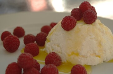 Delicious breakfast of cottage cheese, honey and raspberries on a white plate