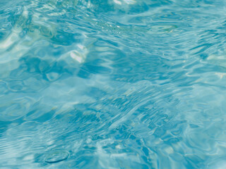 Aqua Background - Photograph of rippled, light blue aqua hued water in public water fountain, illuminated by afternoon sun.
