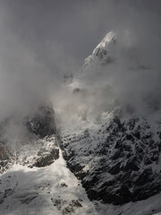 Snowy mountain landscape on a cloudy day with the peaks covered with clouds