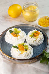 Delicious Mini Pavlovas topped with Fresh Fruit and Cream for dessert on colorful background. Vertical