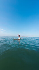 Sportsman paddling on sup board under blue sky on calm water