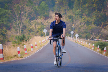 Handsome young man in a blue shirt and black sports shorts is happily riding a bronze and blue...