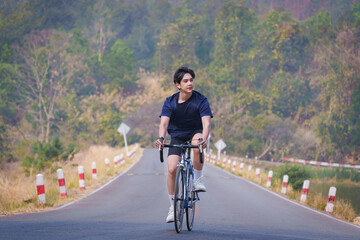 Handsome young man in a blue shirt and black sports shorts is happily riding a bronze and blue...