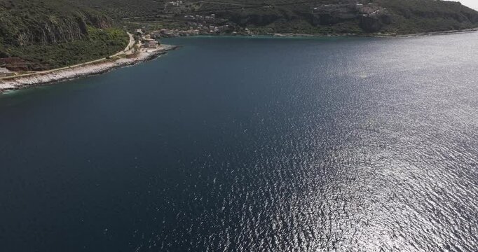Aerial fly towards small coastal town of Limeni, Greece on a sunny spring morning in the Peloponeese.