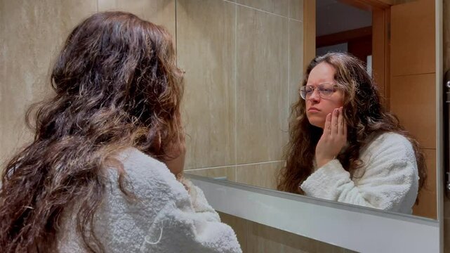 Woman checking her teeth in bathroom mirror