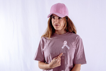 Woman wearing pink ribbon and pointing to it for breast cancer awareness