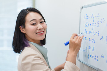 Smiling woman teaching math at a whiteboard in a bright classroom during daytime