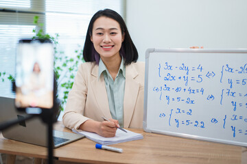 Teacher conducting an online math lesson with whiteboard explanations and video conferencing setup