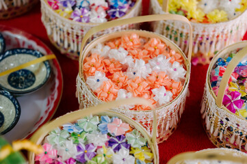 In Thai Buddhist tradition, “Boon coins” or “folded offering coins” are small coins wrapped beautifully in decorative paper or ribbon, often shaped like flowers or other intricate designs.