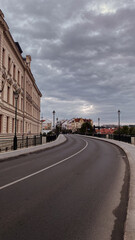 Fototapeta premium A winding road through an old European city, with historical buildings and cloudy sky.