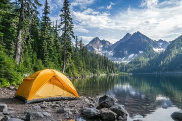 Camping tent pitched lakeside surrounded by forest and snow capped mountains.