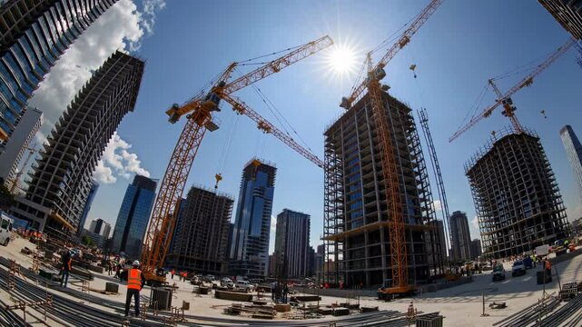 Urban construction site with tower cranes and highrise buildings under clear blue sky