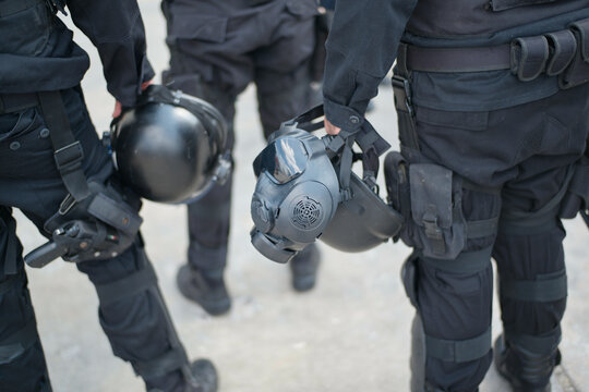Three officers in tactical gear hold helmets in an urban environment. Mexico City, Mexico