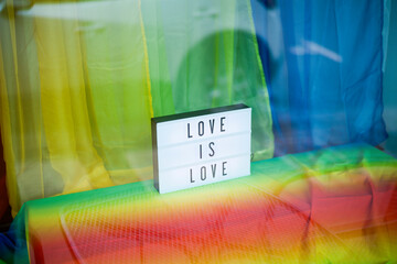 Illuminated sign displaying Love Is Love against a vibrant rainbow background. Oregon, USA