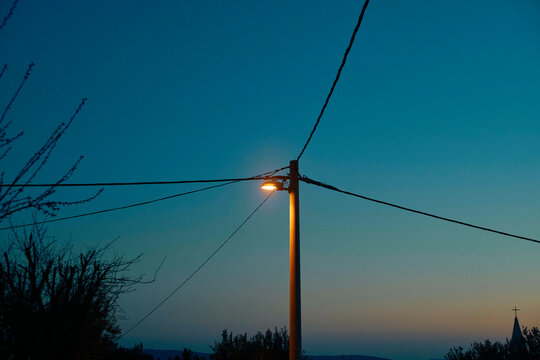 Streetlight against an evening sky with silhouetted trees and power lines. Split, Croatia