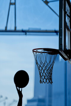Silhouette of a basketball being shot towards a hoop with a blue sky background. New York City, USA