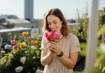 Happy woman smelling a bouquet of freshly picked flowers in a rooftop garden, enjoying her hobby and leisure time